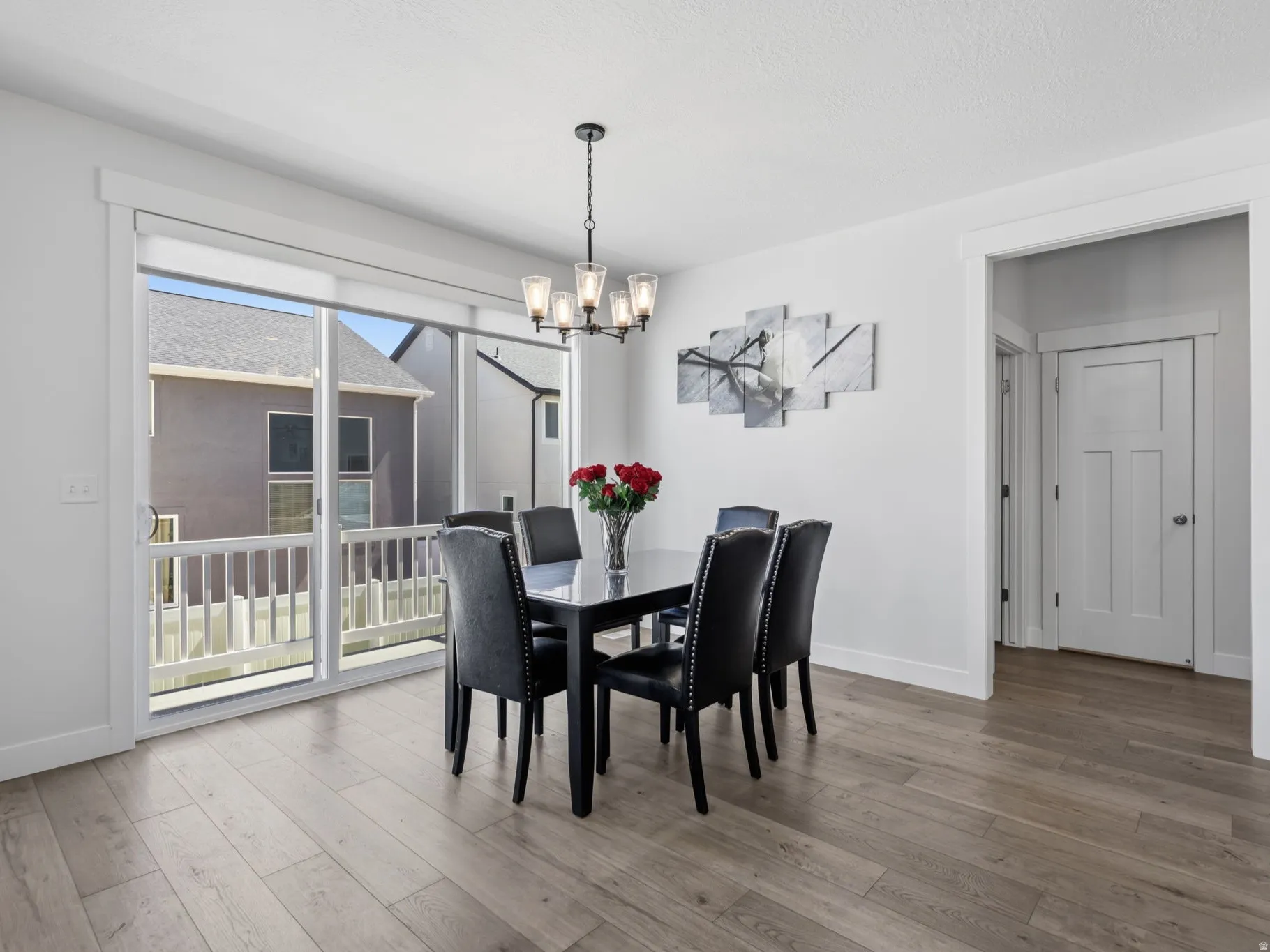 Wood-finish flooring, white trim details, and a sliding glass door to an exterior balcony with white railing