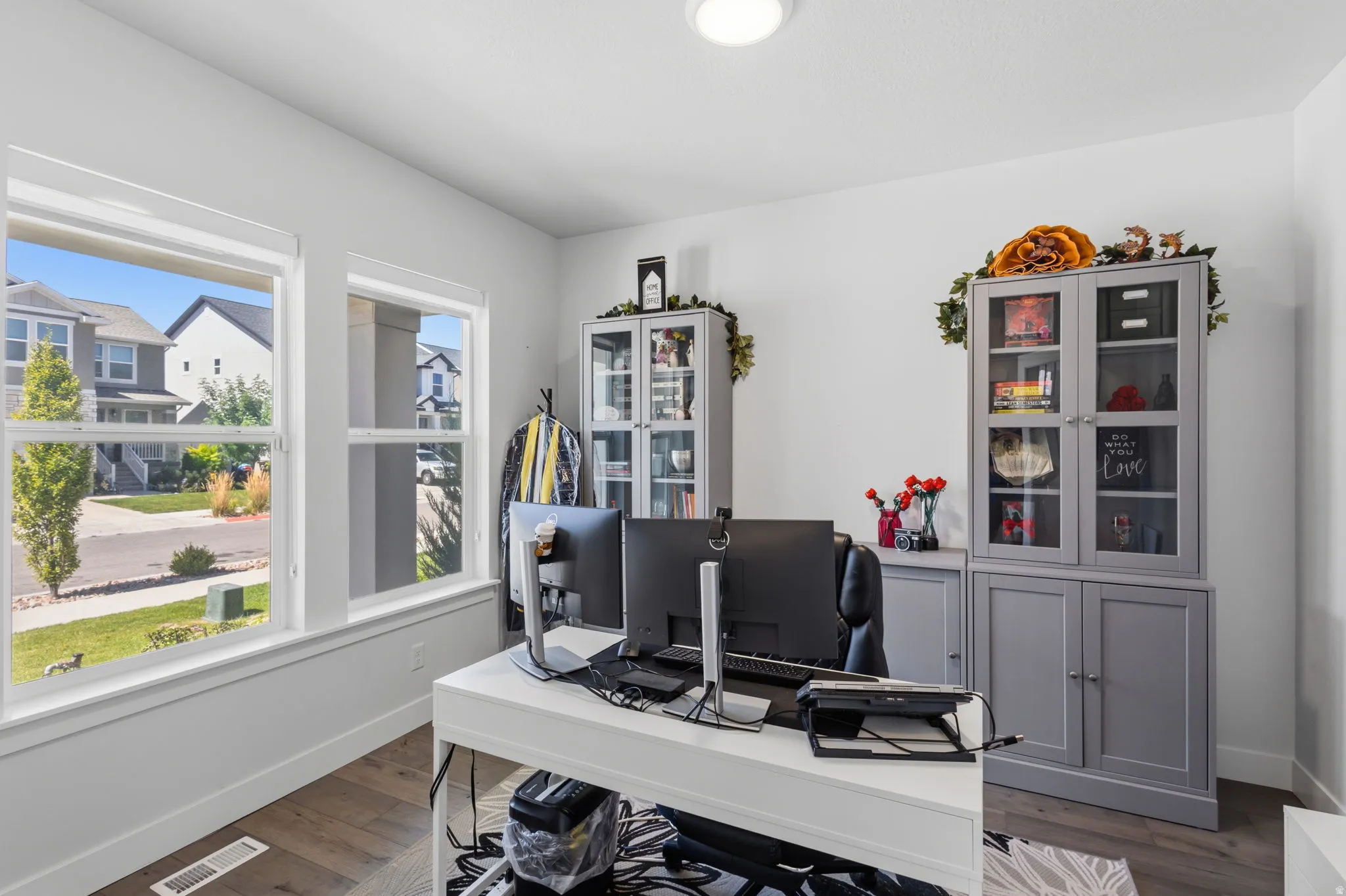 Room with two large windows, wood-finish flooring, and a flush-mount ceiling light