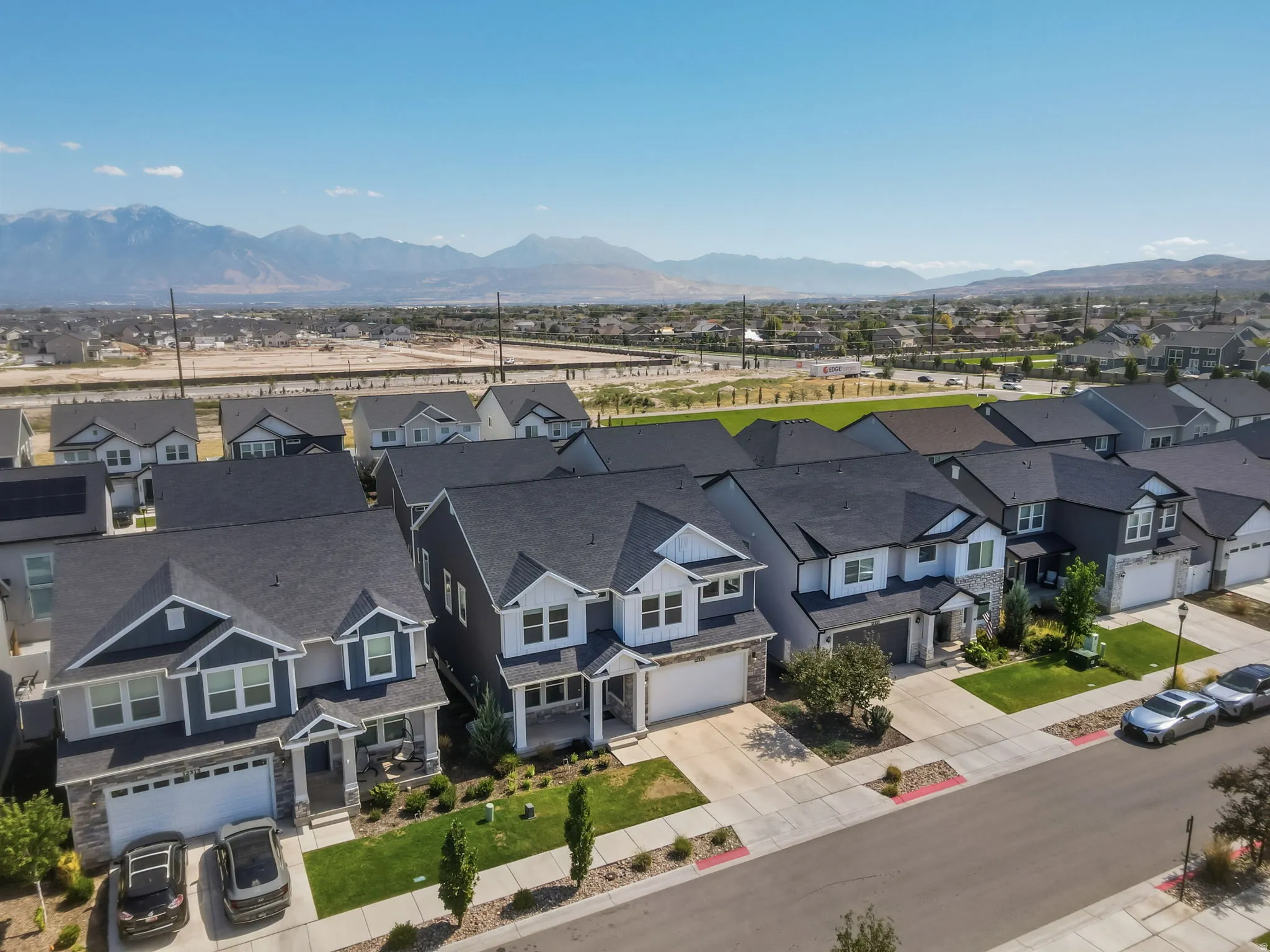 Neighborhood setting featuring a uniform streetscape, mature landscaping, and mountain scenery in the background