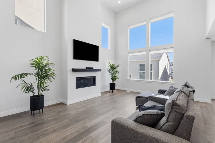 High ceilings, wood-finish flooring, large windows, sleek wall-mounted fireplace, and recessed lighting