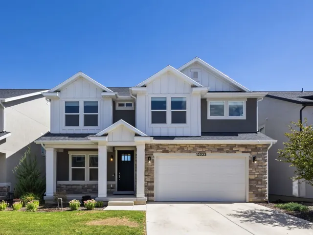 Two-story residence featuring a stone-clad garage, white overhead garage door, and a covered porch entry