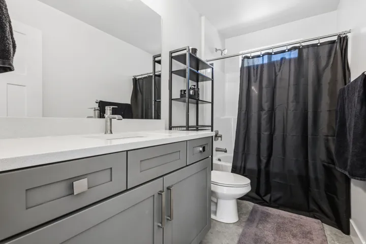 Bathroom featuring a single vanity with gray cabinetry, a white countertop, and an integrated sink