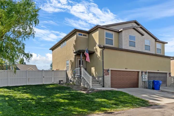 Two-story exterior with stucco and shingle siding, featuring multiple windows, a covered entry, and an attached garage with a paved driveway