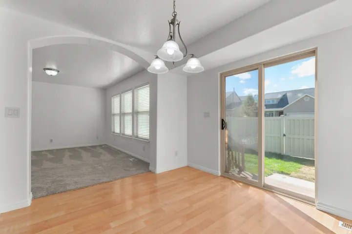 Wood-finish flooring, sliding glass door, overhead lighting fixture, and arched entryway