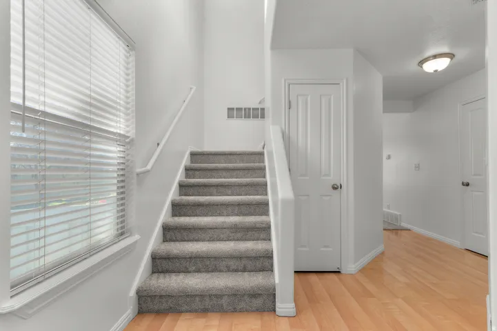Interior staircase with carpeted treads and risers, complemented by a white handrail and trim