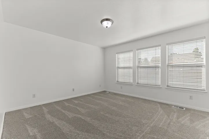 White painted walls with three windows featuring horizontal blinds
