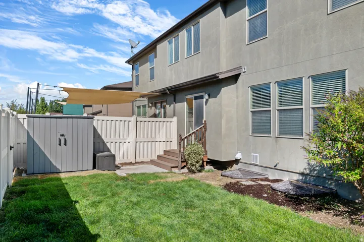 Expansive backyard featuring a manicured lawn, multi-level privacy fencing, and a sun shade structure