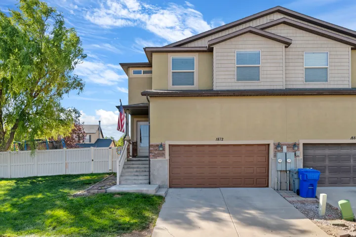 Multi-level stucco exterior with a prominent front entrance, an attached garage, and a white privacy fence