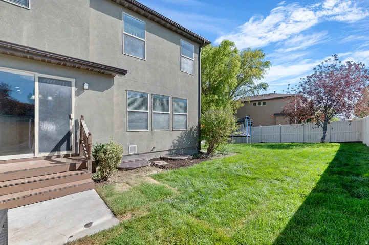 Expansive rear lawn area with mature trees and a privacy fence
