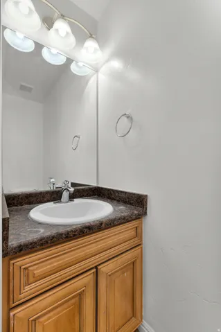 Vanity featuring a white oval sink, chrome faucet, and wood-finish cabinetry