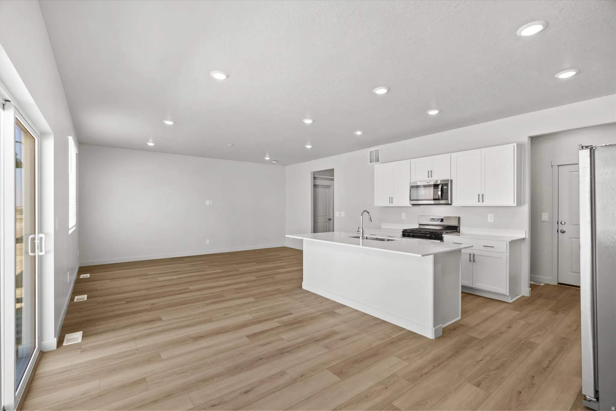 Open-concept living area with wood-finish flooring, recessed lighting, and white walls