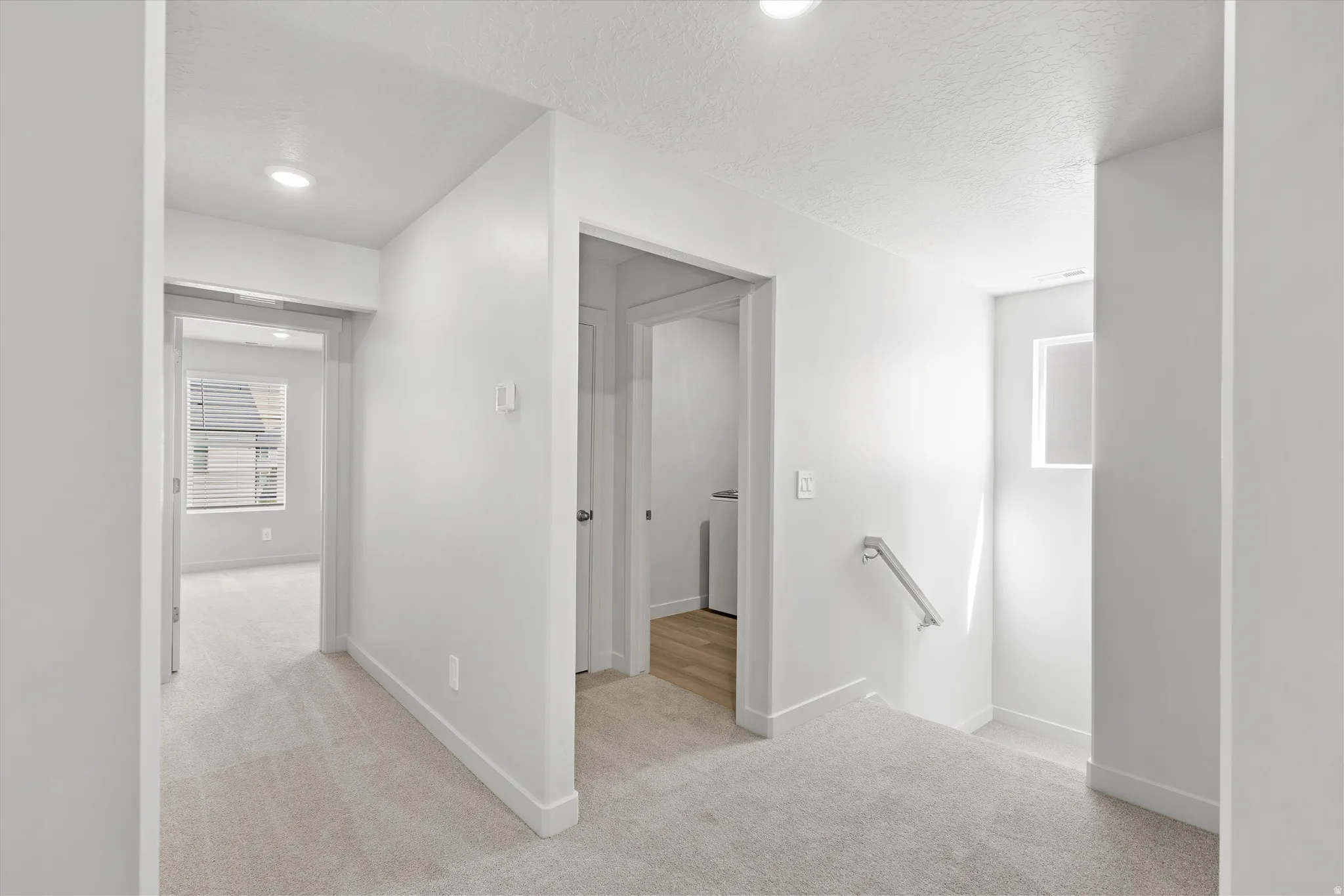 Recessed lighting, light-toned carpeting, and a built-in handrail
