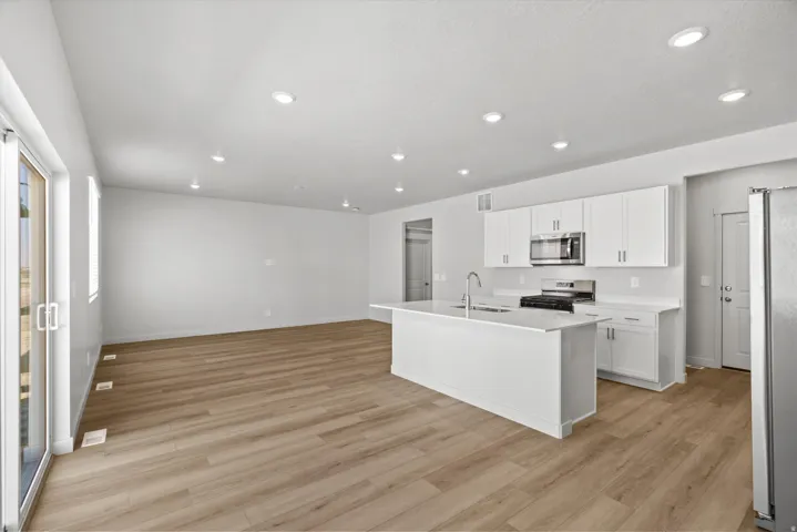 Open-concept living area with wood-finish flooring, recessed lighting, and white walls