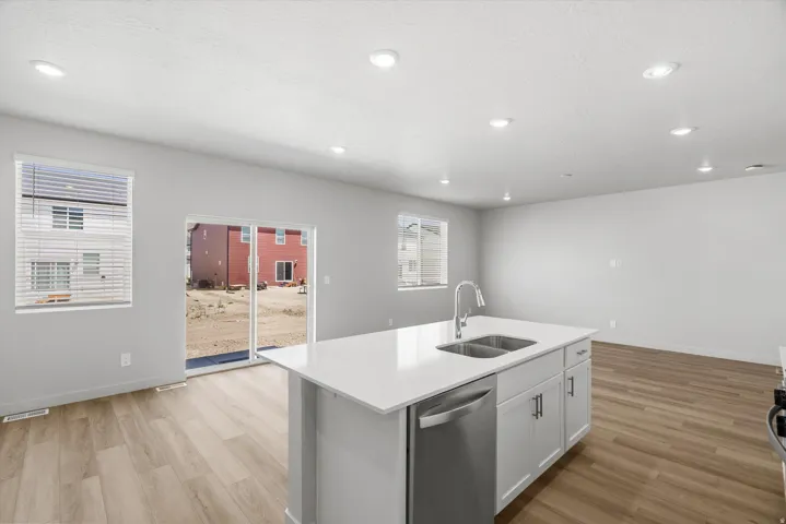 Kitchen island with white countertop, undermount double basin sink, and stainless steel dishwasher