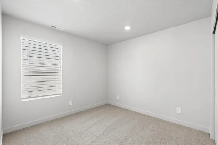 Soft-toned walls, recessed lighting, and light-colored carpeting