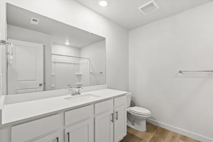 White vanity with an integrated rectangular sink, chrome faucet, and expansive mirror