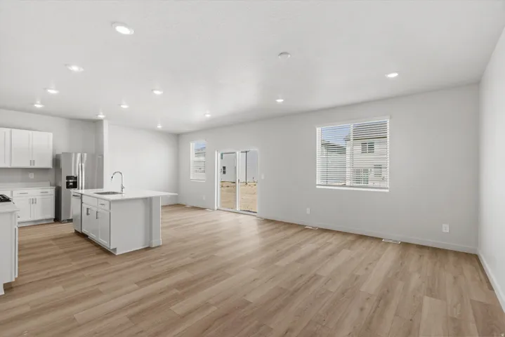 Open-concept living space featuring wood-finish flooring, recessed lighting, a kitchen island with seating, and sliding glass door access to the exterior