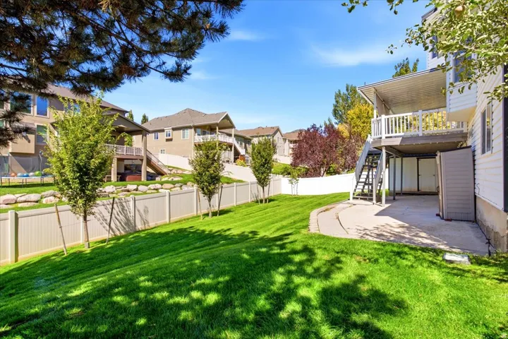 Expansive sloped lawn with a white privacy fence