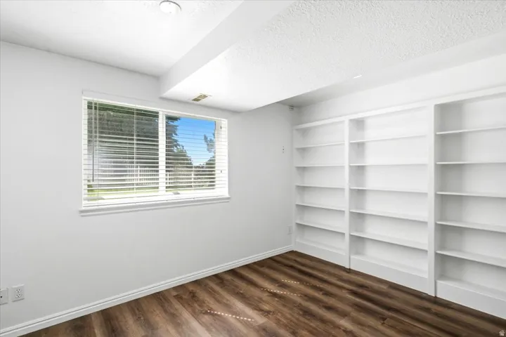Built-in shelving, wood-finish flooring, white walls, window with blinds, and recessed lighting