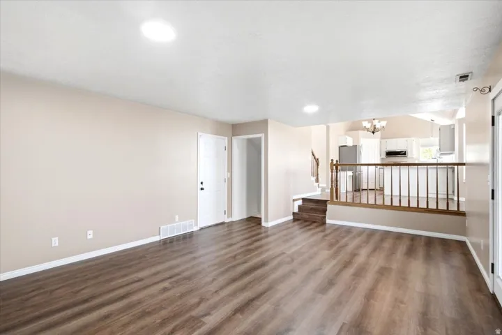 Expansive living area with wood-finish flooring, recessed lighting, and a neutral color palette