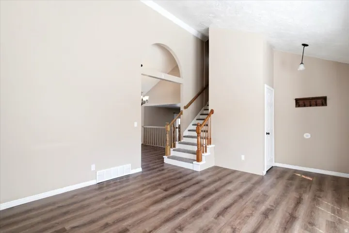 Wood-finish flooring throughout, vaulted ceilings, and a staircase with wood railing