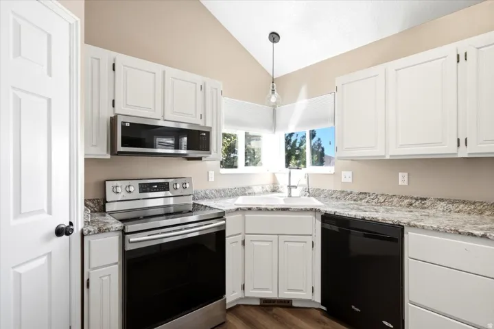 White cabinetry, speckled countertops, stainless steel range, and built-in microwave
