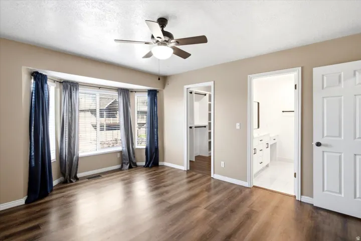 Bay window, wood-finish flooring, ceiling fan, walk-in closet, and an attached bathroom