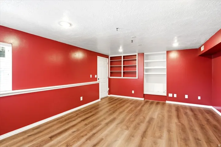 Wood-finish flooring, built-in shelving, built-in cabinetry, recessed lighting, and a white interior door