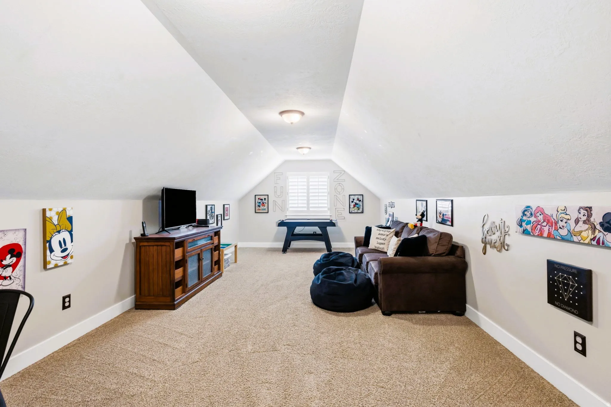 Upstairs oversized carpeted bonus room, featuring sloped ceilings, recessed lighting, and a window with plantation shutters