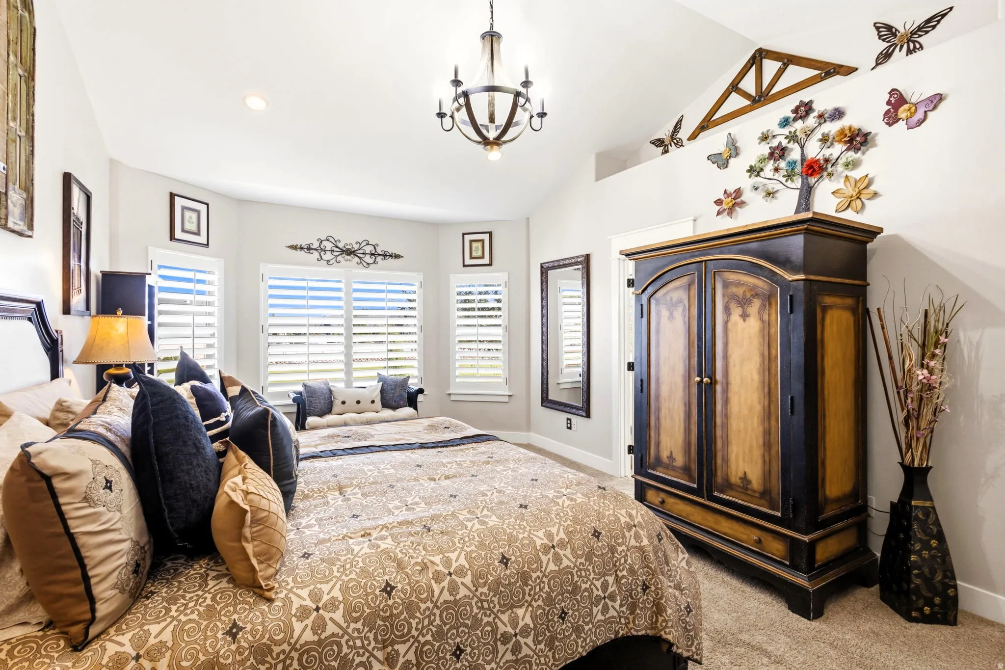Primary bedroom, vaulted ceiling with a chandelier, bay window with plantation shutters, recessed lighting.