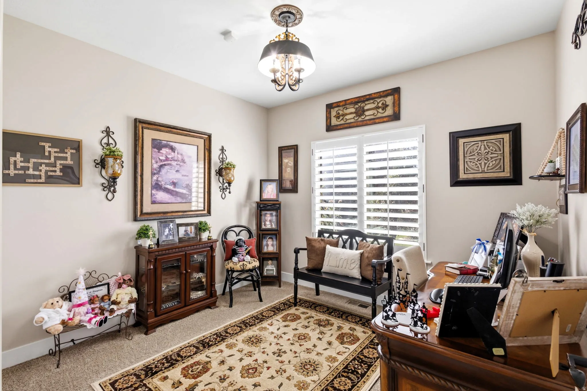 Bedroom #2, Well-lit interior with neutral wall tones and a decorative chandelier and plantation shutters. Used as an office.