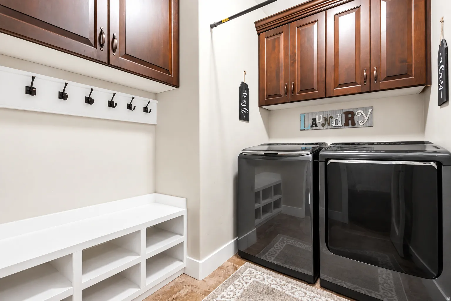 Built-in white storage bench, dark wood-finish upper cabinetry, and a white coat rack with black hooks