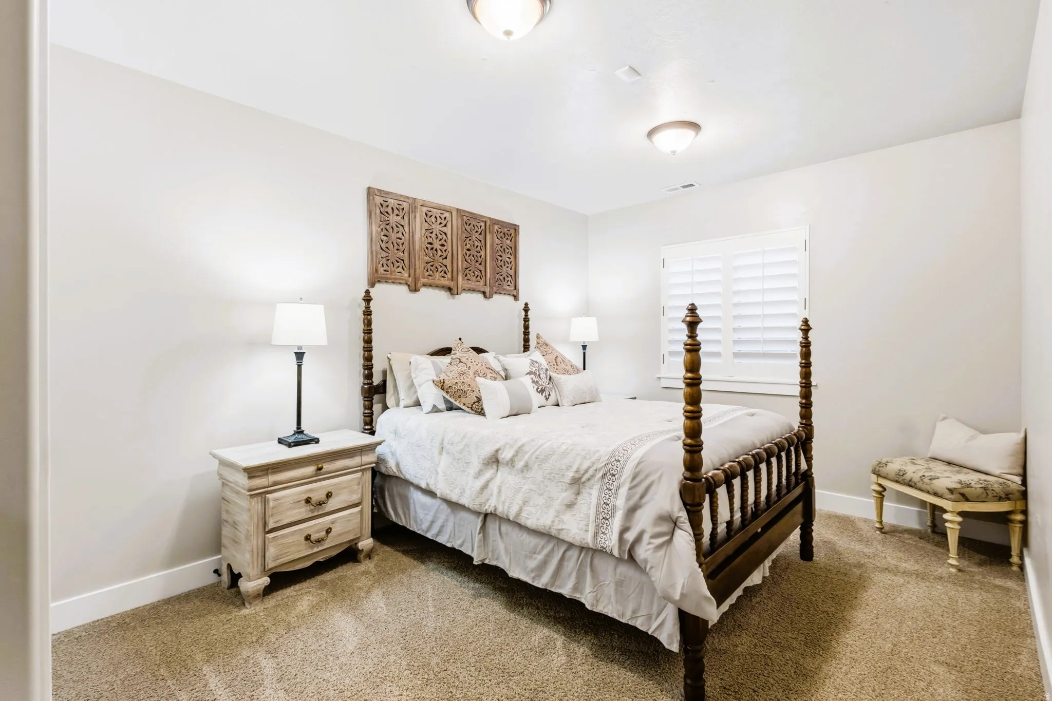 Bedroom #4, featuring window with plantation shutters, overhead lighting, and neutral wall color and carpet.