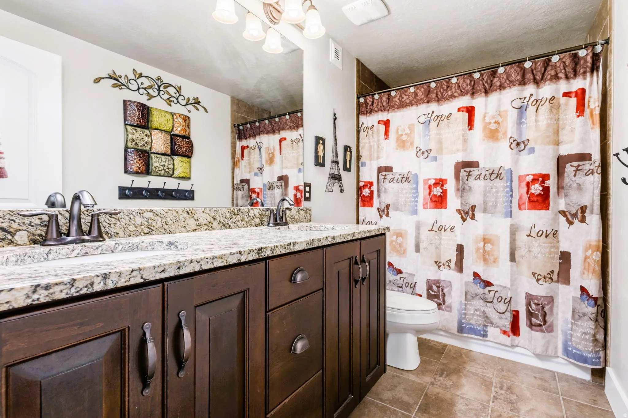 Dual vanity with granite-style countertop, dark wood-finish cabinetry, and oil-rubbed bronze fixtures