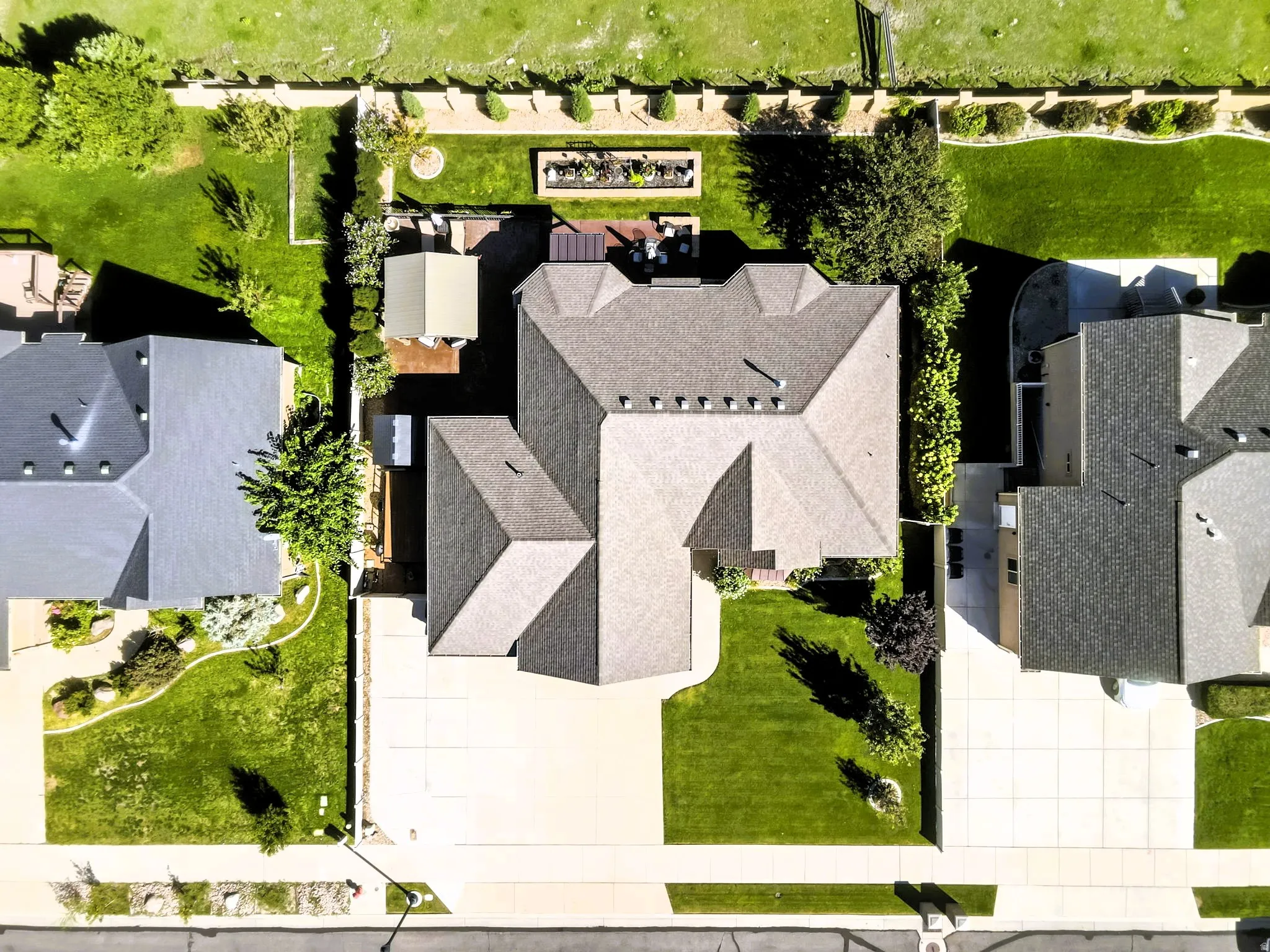 Birds eye view, expansive property featuring a paved driveway, manicured lawns, mature trees, and a private back patio with plenty of space.