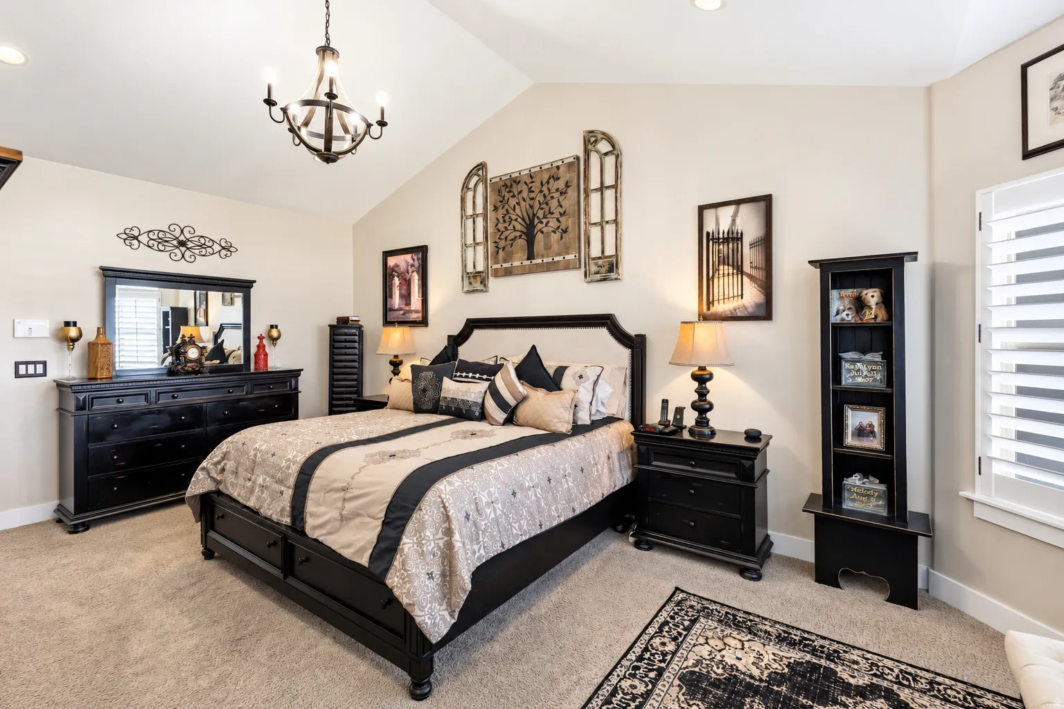 Primary bedroom, vaulted ceiling with an iron chandelier, light-toned walls, recessed lighting, and window with white plantation shutters
