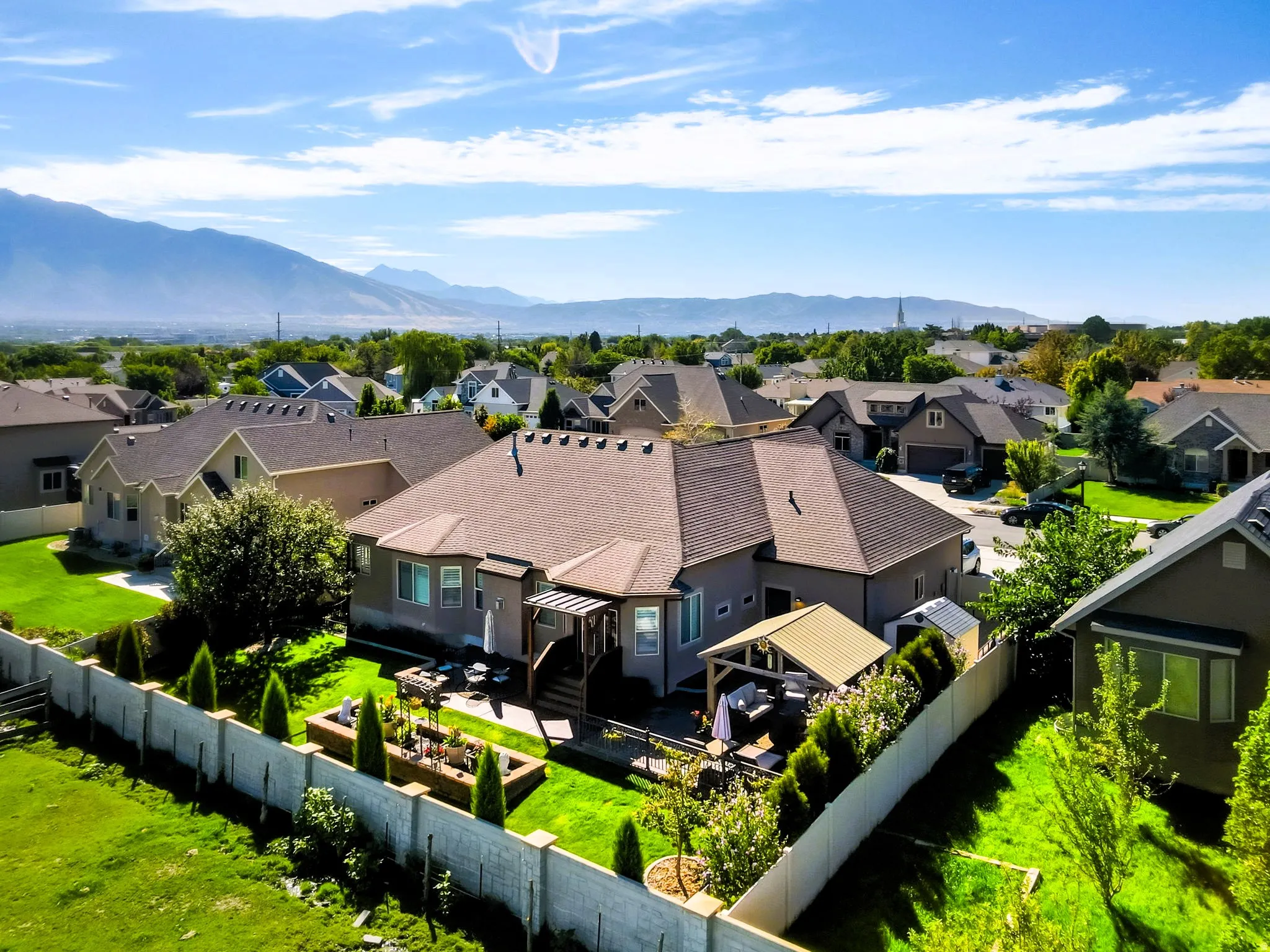 Expansive backyard featuring a manicured lawn, established landscaping, privacy fencing, and a covered patio structure