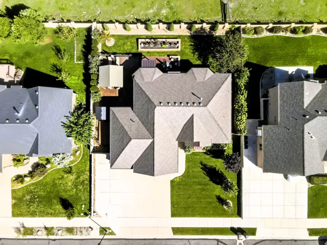 Birds eye view, expansive property featuring a paved driveway, manicured lawns, mature trees, and a private back patio with plenty of space.
