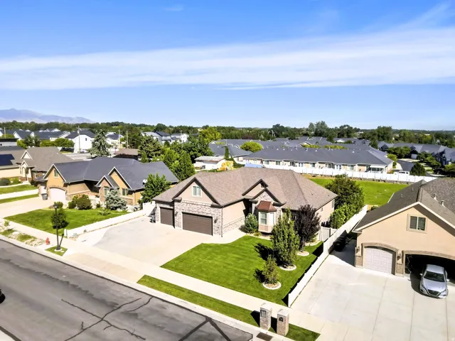 Front exterior featuring stone and stucco finishes, a multi-car garage, manicured lawn, and mature landscaping