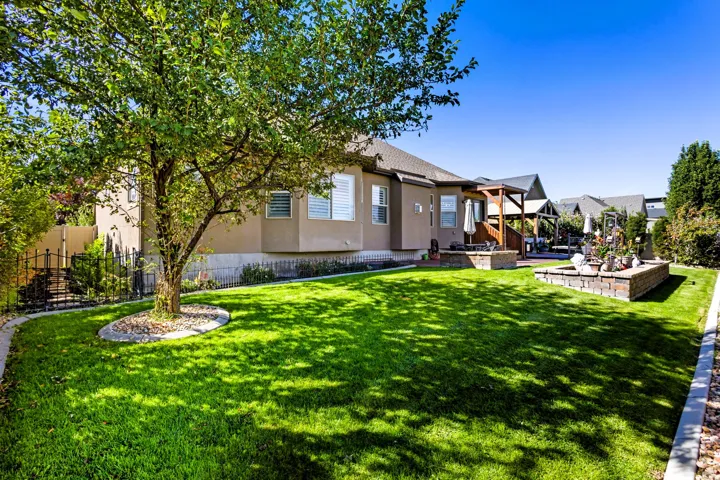 Expansive manicured lawn with a mature shade tree and decorative rock bed