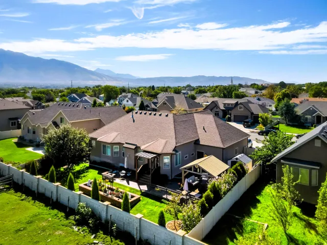Expansive backyard featuring a manicured lawn, established landscaping, privacy fencing, and a covered patio structure