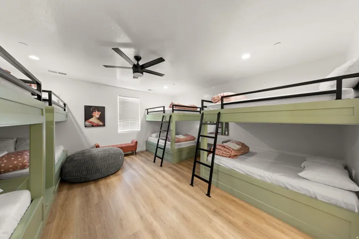 Spacious room featuring multiple built-in bunk beds, wood-finish flooring, a ceiling fan, and recessed lighting