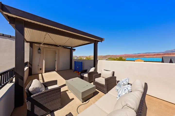 Expansive rooftop deck featuring a pergola, concrete flooring, and an exterior wall lantern