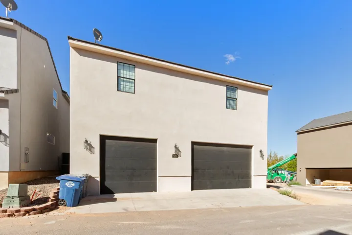 Stucco exterior with a two-car garage, upper-level windows, and exterior wall sconces
