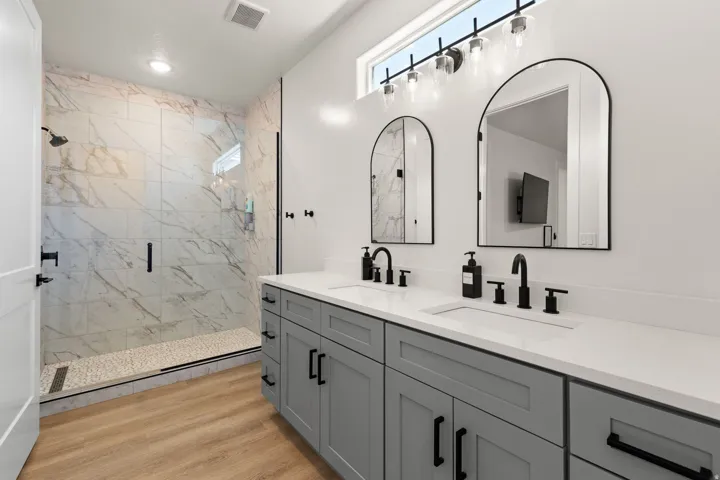 Double vanity with shaker-style cabinetry, quartz countertops, and matte black fixtures