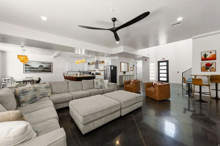 Open-concept living area featuring a modern ceiling fan, recessed lighting, and dark, polished flooring