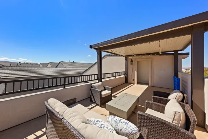 Rooftop patio with a partial shade structure, metal railing, and a solid exterior door