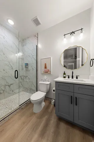 Glass-enclosed shower with marble-look tile surround and pebble floor