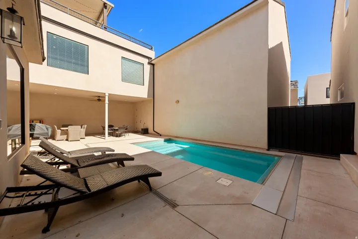 Private outdoor living area featuring a rectangular pool, concrete patio, and a covered patio area with a ceiling fan