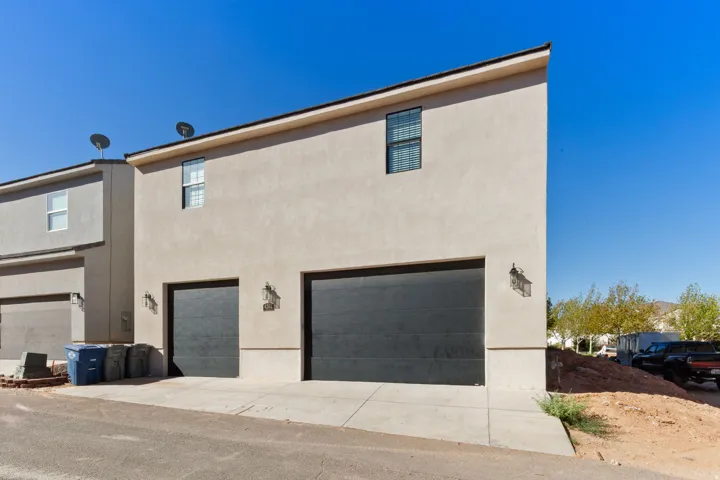 Stucco exterior with two large garage doors, accented by two wall-mounted light fixtures